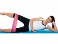 Fit girl on white lying on the mat and doing resistance band workout