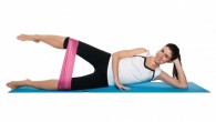 Fit girl on white lying on the mat and doing resistance band workout