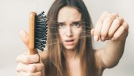 a beautiful girl on white background with a brush full of hair showing how much hair she lost