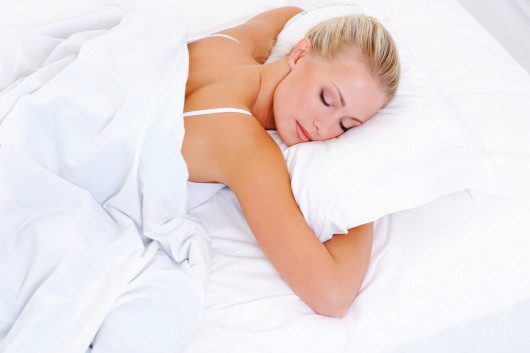 Girl sleeping on her belly and her arms around the pillow