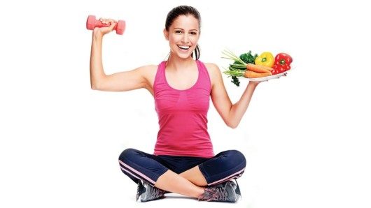 A beautiful sporty girl holding a dumbbell and a place with vegetables