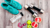 Running shoes, dumbbells, water bottle and fruit are on the wooden background