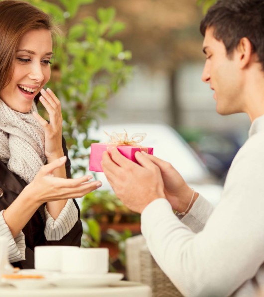 A guy is giving a girl a surprise and she is happily accepting it