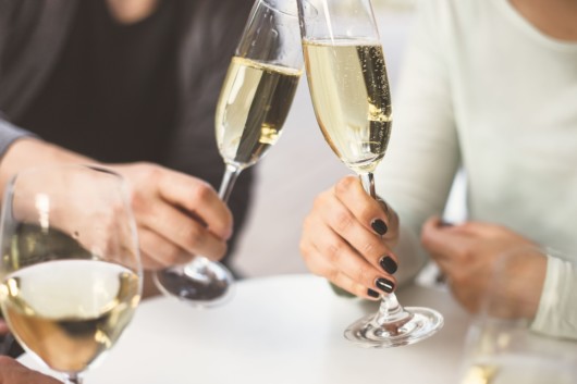 A man and a woman are sitting at the table with 2 glasses of champagne 