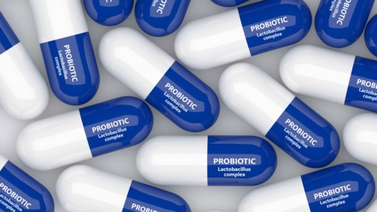 Probiotic supplements in white and blue capsules on white 