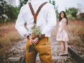 A romantic guy with flowers behind his back and the girl stands in front of him. they are both outside