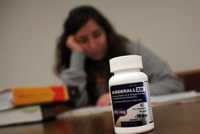 Girl is sitting at the table where there are books and adrenal pills