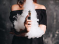 Girl holding vape and releasing the smoke