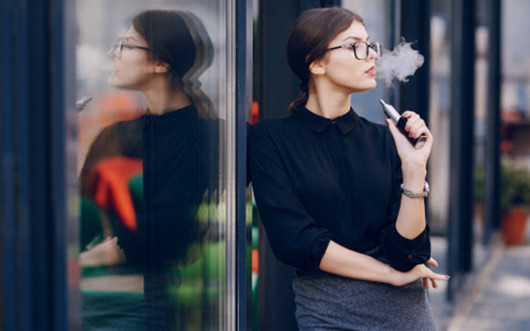 Girl in glasses vaping outside