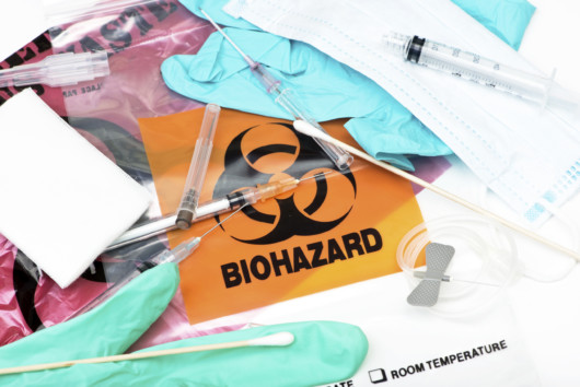 Biohazard waste bags with used syringes, needles, bandages, and other medical waste.