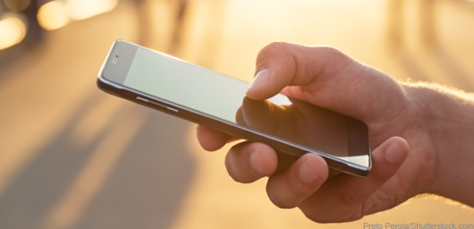 A guy is holding a sell phone in his hands