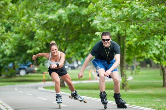 A man and a woman are having fun in rollerblading in the park