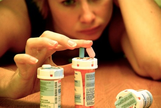 Girl looks at the bottle of pills and holding the pills in her fingers