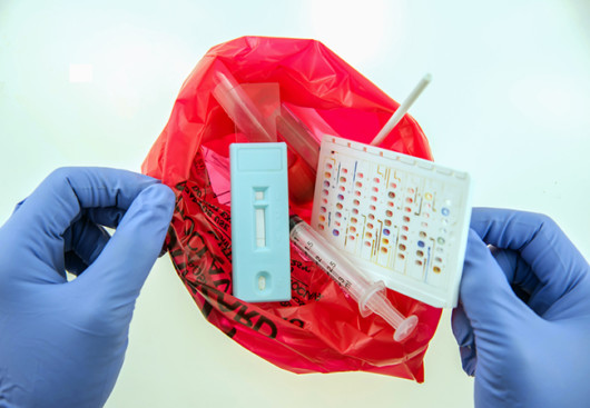 a person holds a red package of medical waste in his hands