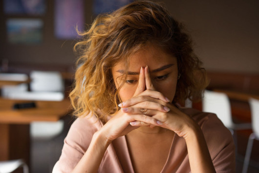 A girl is puzzled and sad. She keeps her fingers at her forehead