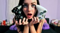 A girl is holding two gamepads close to her face and opens her mouth in surprise