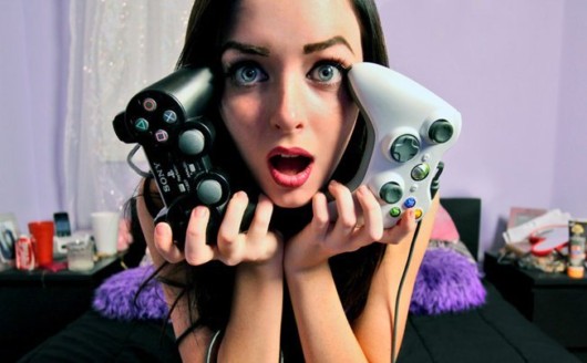 A girl is holding two gamepads close to her face and opens her mouth in surprise