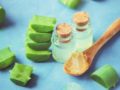 Aloe vera leaves and gel in the spoon on blue background