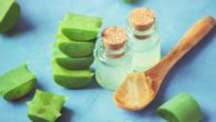 Aloe vera leaves and gel in the spoon on blue background