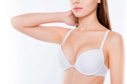 A girl in white bra on white showing her breast after breast augmentation