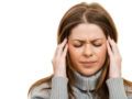 A girl in grey sweater on white is touching her temples because of the migraine