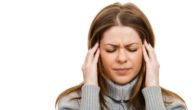 A girl in grey sweater on white is touching her temples because of the migraine