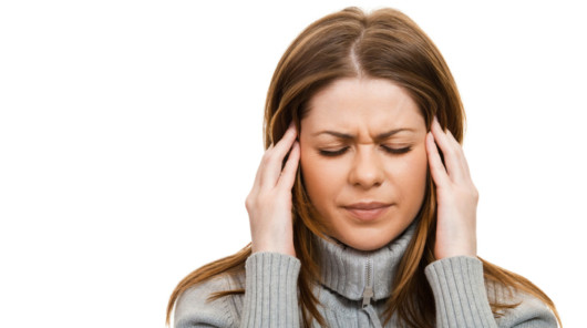 A girl in grey sweater on white is touching her temples because of the migraine