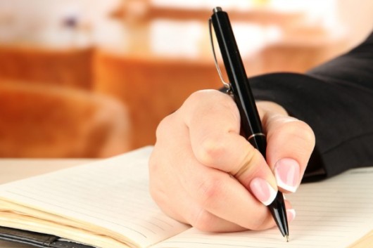 Close up girl's hand with a black pen and a notebook