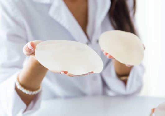 Saline or silicone filling agents are used in breast augmentation operation. The doctor is holding breast implants 