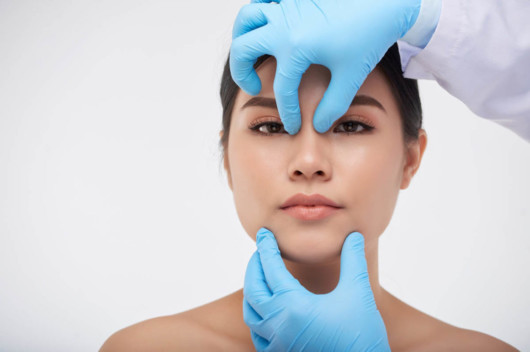 A doctor is examining the girl nose before nonsurgical rhinoplasty