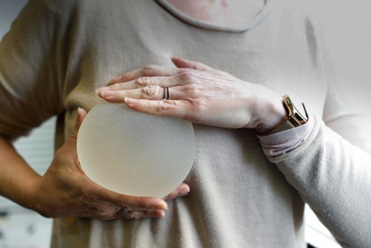 A woman is checking the size of a silicon breast implant to check if it fits her.