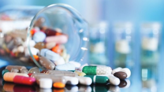 Colourful capsules and pills are scattered on the table