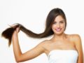 A beautiful and young girl on white background holding her long dark hair in her hands