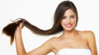 A beautiful and young girl on white background holding her long dark hair in her hands