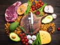 Meat, fish, avocado, greens, nuts and tomatoes with knife and fork on the wooden cutting board