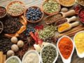 Herbs, spices, berries in plates and spoons on wooden background