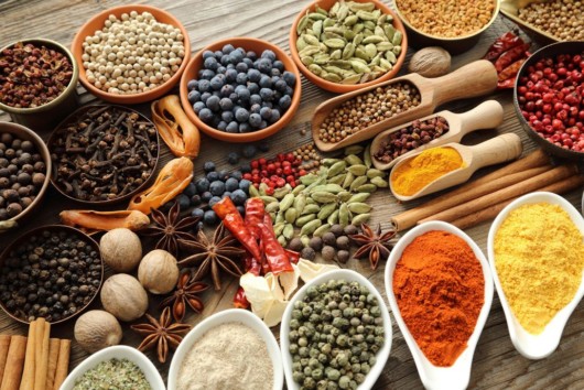 Herbs, spices, berries in plates and spoons on wooden background