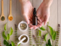 A bottle of cbd oil lies in the hands with herbs and leaves on the wooden background