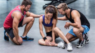 Girl in the gym sitting on the floor with a sprained ankle