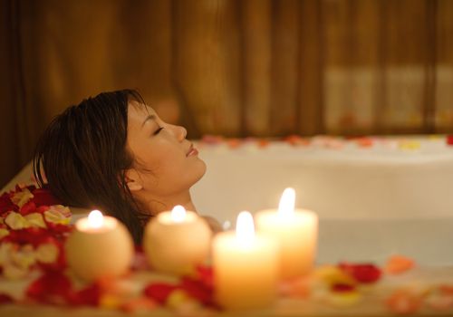 Girl is relaxing by taking aroma bath with candles