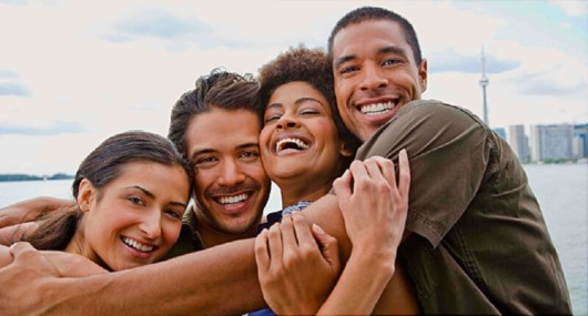 Four happy people are embracing and smiling 