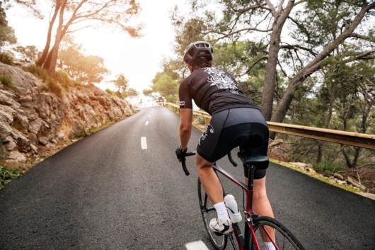 The girl in helmet is cycling along the road