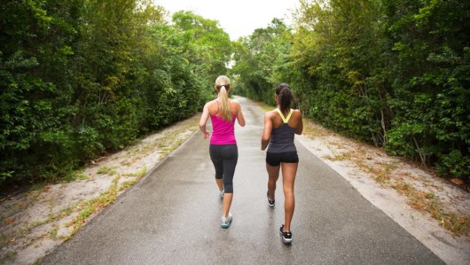 Two sporty girls in gym outfit are walking in the park. 