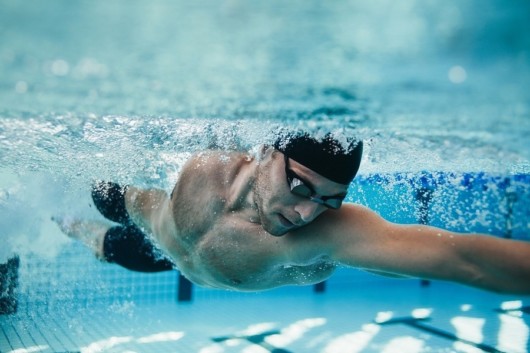 A professional swimmer is swimming in the pool