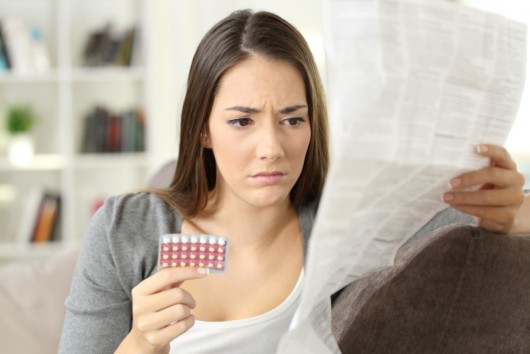 A girl is reading a birth control instruction and information before taking 