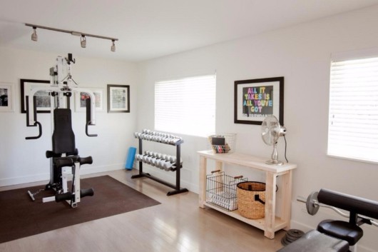 A room with gym machines and dumbbells. The bedroom is used as a home gym