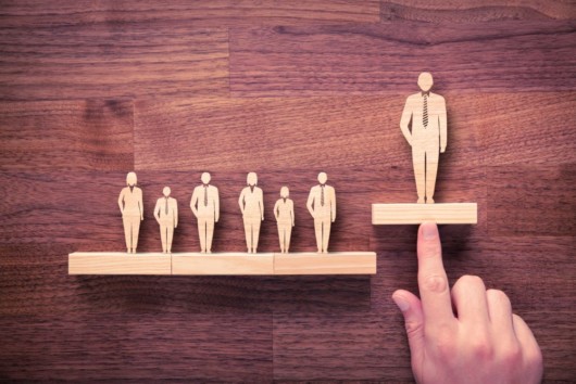 A wooden figures of people on the dark wooden background showing the professional development