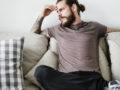 A guy sitting on the sofa with his fingers on his forehead and thinking deeply