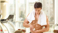 Muscular young man taking pills in gym