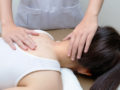 Girl is lying on the massage table while chiropractor checking her neck and spine